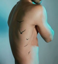 a man with tattoos on his back is looking off to the side and has birds drawn on his chest