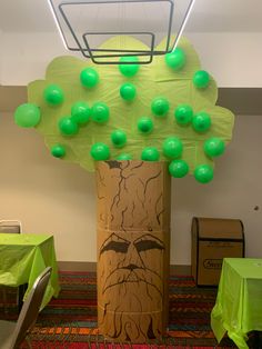 a tree with green balls on it in the middle of an office space, surrounded by tables and chairs