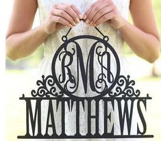 a woman holding up a metal monogrammed cake topper