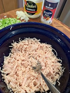 a bowl filled with shredded meat next to some chopped green onions and mayonnaise