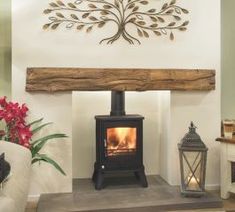 a wood burning stove in a living room next to a vase with flowers on it