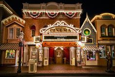 the entrance to an amusement park lit up at night with lights on it's sides