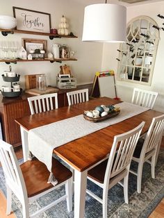 a dining room table with white chairs and a light hanging over it