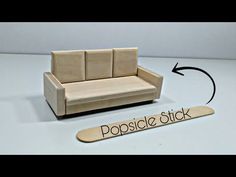 a wooden couch sitting on top of a table next to a sign that says popsicle stick