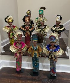 a group of african dolls standing on top of a wooden floor next to a stair case