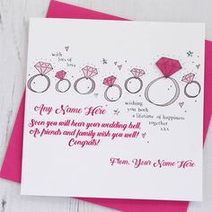 a card with some wedding rings and diamonds on it's side, next to a pink envelope