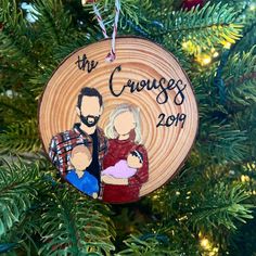 a christmas ornament hanging on a tree with a photo of two people holding a baby