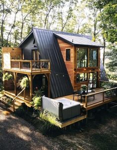 a small wooden cabin in the woods with a deck and hot tub on the porch