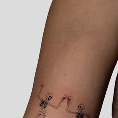 skeleton tattoos on the leg of a woman holding a glass of wine and two cats