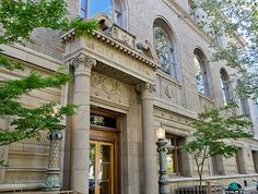 the front entrance to an old building with stone columns and arched windows, on a sunny day