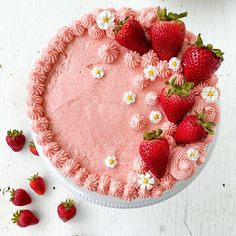 there is a cake with strawberries on it and flowers around the edges that are pink