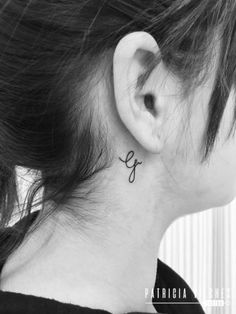 a woman's ear with the letter g on it, behind her ear is a black and white photo