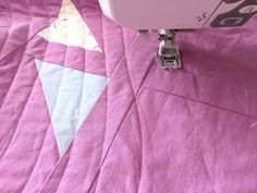 the sewing machine is on top of the pink quilted bedding with an ice cream cone