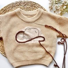 a sweater with an elephant drawn on it next to some flowers and twine cord