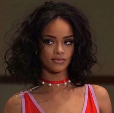 a close up of a person wearing a red shirt and choker with pearls on it