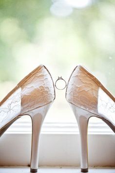 a pair of white high heels sitting on top of a window sill