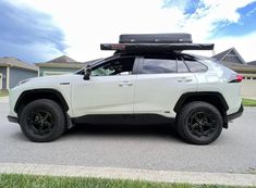 a white suv parked on the side of a road with its roof rack mounted to it's back