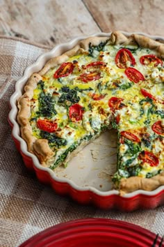 a quiche with cheese, tomatoes and spinach in a pie pan on a table