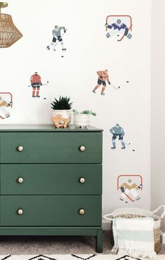 a green dresser sitting in front of a wall with hockey decals on the walls