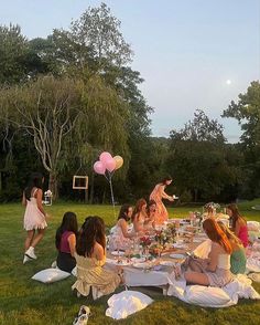 a group of women sitting around a table with pink balloons in the shape of hearts