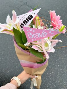 a person holding a bouquet of flowers with a sign that says brave on it's side