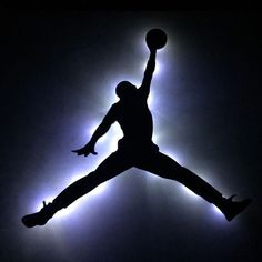 the silhouette of a basketball player jumping in the air