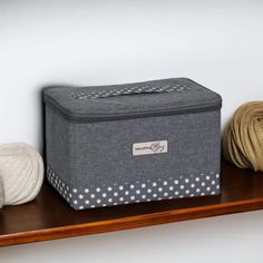 two balls of yarn are sitting on a shelf next to a storage box and ball of yarn