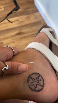 a woman's foot with a sand dollar tattoo on it