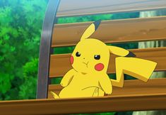 a pikachu sitting on a park bench