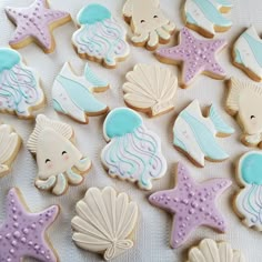 there are many decorated cookies on the table together, including little mermaids and seashells