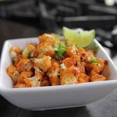 a white bowl filled with food next to a lime wedge