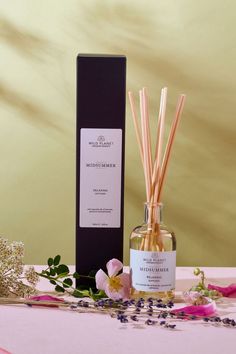 Midsummer Reed Diffuser next to black branded box with fresh lavender and geranium flowers by Wild Planet Aromatherapy Relax And Unwind, Wax Melts