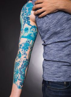 a man with a blue and white tattoo on his arm holding another person's arm