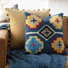 a blue and yellow pillow sitting on top of a brown couch