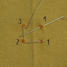 the sewing needle is being used to sew an orange piece of fabric with two needles