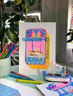 there is a card with a boat on it next to some pencils and markers