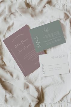 two wedding cards laying on top of a white sheet covered in sheets and laces