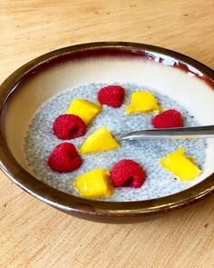 a bowl filled with oatmeal topped with raspberries and pineapple