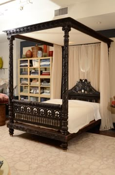 a bedroom with a four poster bed and white curtains