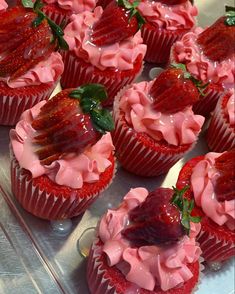 strawberry cupcakes with pink frosting and fresh strawberries on top are ready to be eaten