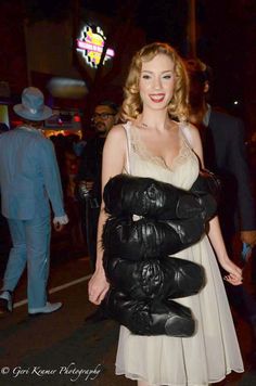 a woman in a white dress and black leather gloves is standing on the street at night