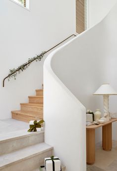 a white staircase leading up to a table with two vases and a lamp on it