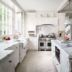 a large kitchen with white cabinets and marble counter tops, along with an island in the middle