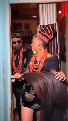 a man and woman standing next to each other in front of a doorway with beads on them