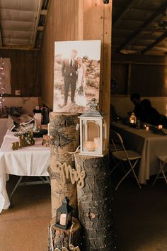 a wooden post with pictures and candles on it in front of a white table cloth