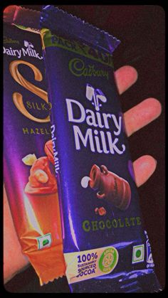 someone holding two dairy milk chocolate bars in their hand