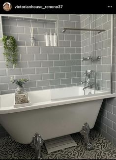 a white bath tub sitting in a bathroom next to a shower head and hand held faucet