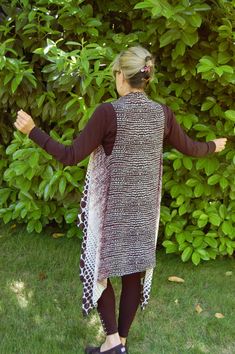 a woman standing in the grass with her arms spread out, wearing a brown and white dress