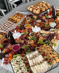 a table filled with lots of food on top of a white wooden floor next to chairs