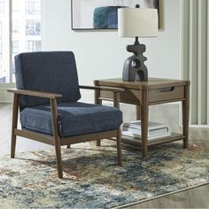 a blue chair sitting on top of a rug next to a table with a lamp